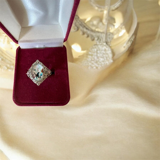 Anillo de filigrana plateado con diseño de mariposas y detalles en piedras rosas.